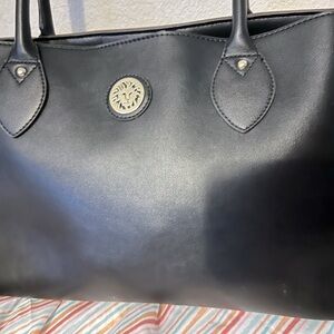 Anne Klein’s solid black bag with several large compartments three snap closure